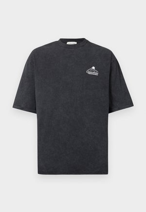 Camiseta negra de manga corta con un pequeño logo blanco de montaña y sol, y el texto "Copacabana Paradise Beach" en el pecho izquierdo.