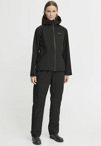 Black waterproof jacket with a zip closure and hood, paired with matching trousers. Material is smooth with a matte finish, minimalistic design.