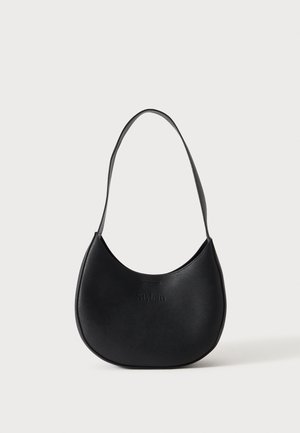 Sac à épaule en cuir noir en forme de croissant avec une bandoulière unique et un nom de marque discrètement embossé sur un fond clair uni.