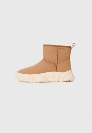 Botte d'hiver couleur fauve montant à la cheville avec une semelle épaisse en caoutchouc blanc, languette de maintien, détails cousus et logo GEOX sur le côté.