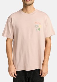 T-shirt en coton rose clair avec un petit design graphique multicolore sur la poitrine gauche, à coupe décontractée et à manches courtes.
