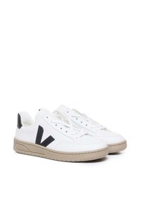 White leather sneakers with a beige sole, featuring a black accent on the heel and a prominent black V logo on the side.
