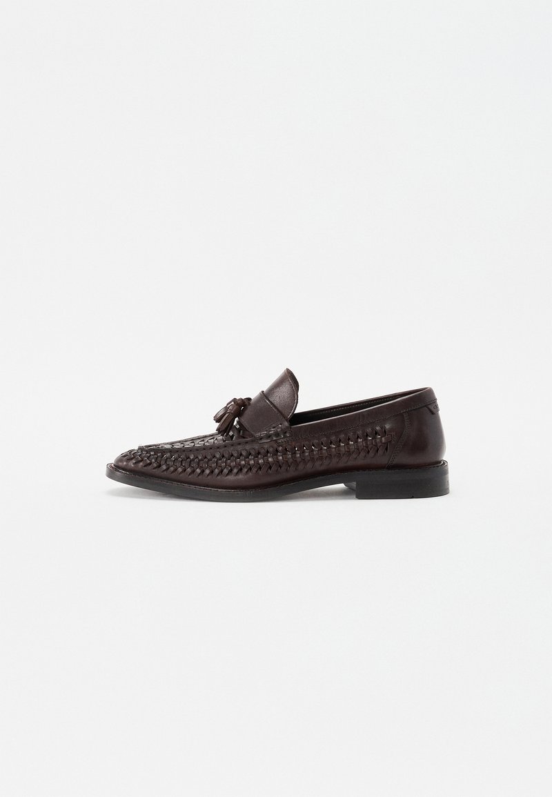 Mørkebrun læder loafers med vævet detalje, flad hæl og en dekorativ kvast foran. Glat tekstur, strømlinet design.
