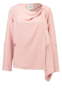 Light pink long-sleeve asymmetrical jacket with button closure near the collar and diagonal zipper pocket on the side.