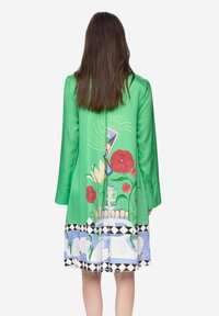 Vestido verde con un estampado floral que incluye flores rojas y cisnes en la parte inferior, mangas largas y una textura suave.