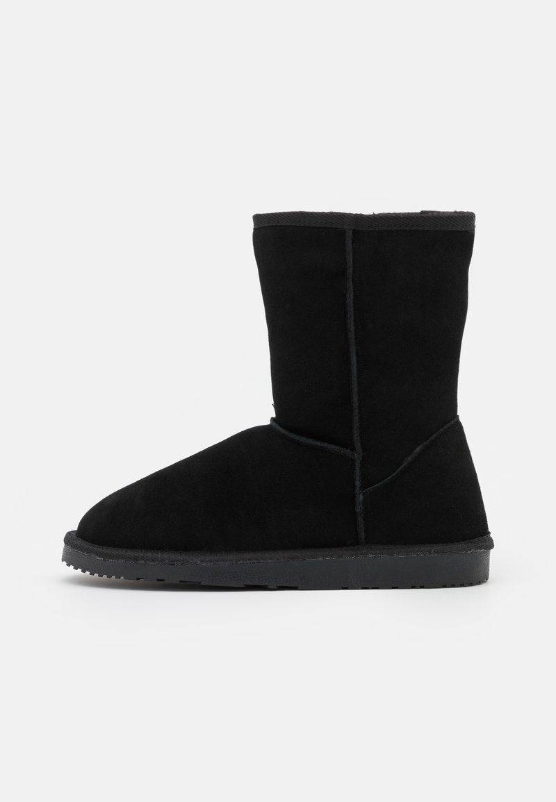 Schwarze Wildleder-Stiefeletten mit abgerundetem Zeh, glatter Textur und flacher Gummisohle. Keine sichtbaren Metallteile oder Muster.