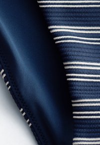 Tissu bleu marine avec texture en maille serrée à côté d'un tissu tricoté rayé bleu marine et blanc, montrant des coutures détaillées et des motifs de tissage.