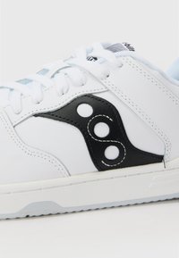 Sneaker bianco con accenti in sintetico neri e un logo caratterizzato da tre dettagli circolari. Materiale testurizzato, design con lacci e suola in gomma.