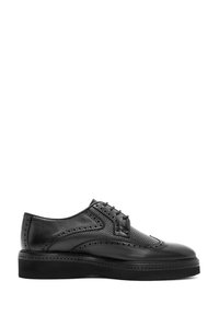 Schwarze Leder-Herren-Brogue-Schuhe mit Wingtipp-Dekor und dicker Sohle, von der Seite auf weißem Hintergrund gezeigt.