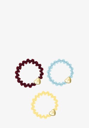 Trois bagues élastiques perlées en rouge, bleu et jaune, chacune avec un petit pendentif cœur en or gravé d'initiales.
