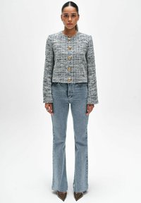 Geweven tweed jasje met een ronde halslijn, gouden knopen en lange mouwen. Gepaard met lichtblauwe flared jeans en puntige schoenen.