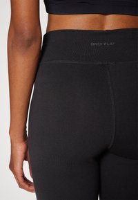 Sorte leggings lavet af glat, strækbart stof. Har en høj talje med "ONLY PLAY" logo. Enkelt design, ingen synlige mønstre.