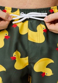 Zwemshorts van groene stof, met een patroon van gele rubberen eendjes. Inclusief een witte trekkoord voor aanpassing.