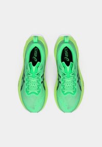 Neon zöld sportcipők hálós felsőrésszel, texturált részletekkel, fekete díszítőelemekkel és hozzáillő fűzőkkel. Párnázott szegély és nyelv jellemzi őket.