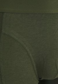 Olivgrüne Herrenunterwäsche aus weichem Baumwollmaterial, ausgestattet mit einem glatten Bund und Flachnahtnähten für Komfort und Langlebigkeit.