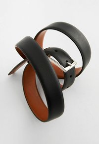 Cinturón de cuero negro con textura suave, que cuenta con una hebilla rectangular de plata y un forro interior marrón. El diseño retorcido muestra flexibilidad.