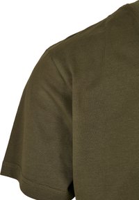 Camiseta de color verde olivo con mangas cortas, textura suave y cuello redondo. La tela parece suave con un ligero brillo. Costuras visibles en el dobladillo.