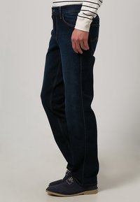 Mörkblå denimjeans med slim fit, med fram- och bakfickor, kontrasterande sömmar och en slät yta.