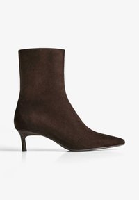 Botine din suede maron închis, cu vârf ascuțit și toc mic, pe fundal alb.