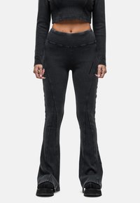Zwarte flared jeans in een geribbelde textuur, met opvallende zijnaad en hoge taille. Draag ze met een bijpassende cropped top.