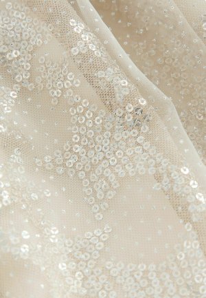 Beige genomskinlig tyg prydd med cirkulära paljetter och små glittrande detaljer, vilket skapar en texturerad, lager-på-lager effekt med stjärnmönster.