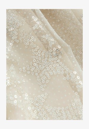 Bežová průhledná tkanina zdobená kulatými flitry a drobnými třpytivými detaily, vytvářející texturovaný, vrstvený efekt se vzory hvězd.