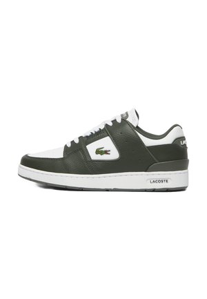Zapatilla de cuero verde con acentos blancos, que presenta una puntera redonda, cierre con cordones, superficie texturizada y un logo de Lacoste. Suela de goma.