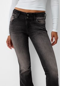 Černé džíny z denimu s vybledlým efektem, vybavené dvěma předními kapsami, dvojitým zapínáním na knoflíky a prošitým zdobením podél švů.