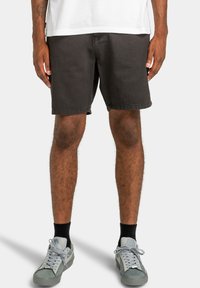 Donkergrijze denim shorts met een rechte snit, zichtbare stiksels en een schone zoom, gecombineerd met lichtgrijze sneakers en zwarte sokken.