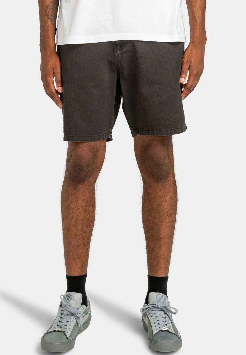Donkergrijze denim shorts met een rechte snit, zichtbare stiksels en een schone zoom, gecombineerd met lichtgrijze sneakers en zwarte sokken.