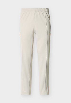 Εκρού στενά παντελόνια φόρμας με ελαστική μέση, πλαϊνές τσέπες και διακριτικό πορτοκαλί λογότυπο στα πάνω μηρά.