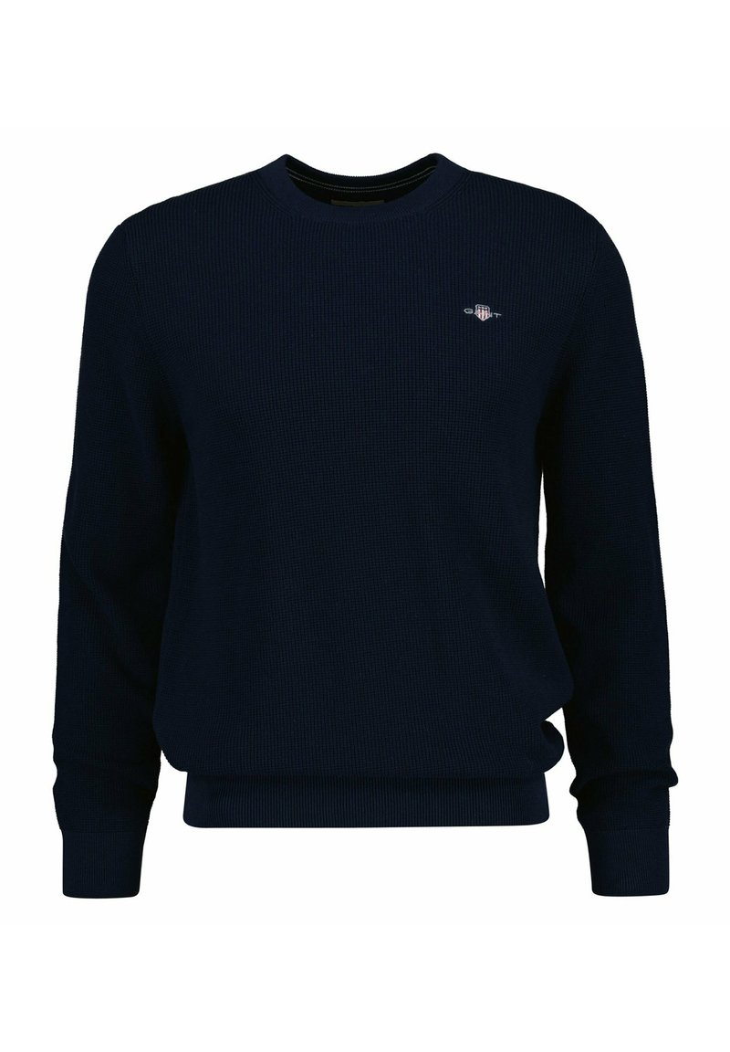 Maglione a girocollo blu navy con maniche lunghe, bordi a coste e un piccolo logo sul petto. Realizzato in un materiale lavorato a maglia confortevole.