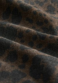 Brauner Stoff mit subtilen Leopardenmuster; verfügt über eine strukturierte, gewebte Oberfläche und einen reichen Farbkontrast zwischen dunklen und hellen Tönen.