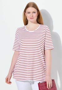 Pruhované tričko s červenými a bílými horizontálními pruhy, kulatým výstřihem, krátkými rukávy a volným střihem. Slučuje se s vinově červeným psaníčkem.