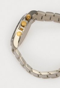 Edelstahl-Uhr mit einem silbernen Gliederarmband, runder Ziffernblatt, goldfarbene Drücker und einem strukturierten Lünette-Design.