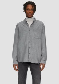 Grijs flanellen overhemd met knopen en een voorzak, casual pasvorm en zwarte knopen. Gestyled over een lichte coltrui en gecombineerd met donkere broek.