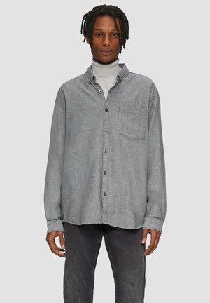 Grijs flanellen overhemd met knopen en een voorzak, casual pasvorm en zwarte knopen. Gestyled over een lichte coltrui en gecombineerd met donkere broek.