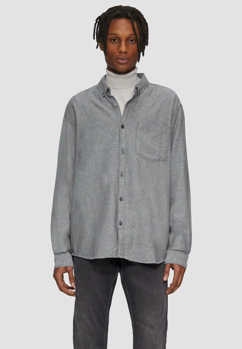 Grijs flanellen overhemd met knopen en een voorzak, casual pasvorm en zwarte knopen. Gestyled over een lichte coltrui en gecombineerd met donkere broek.