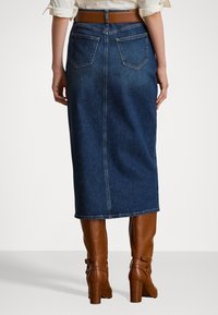 Gonna midi in denim blu scuro con una vita aderente, due tasche posteriori e un orlo che arriva a metà polpaccio. Abbina stivali marroni al ginocchio.