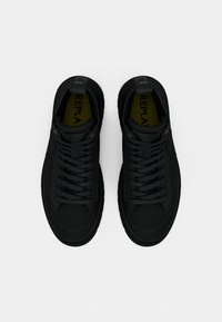 Un paio di sneakers alte nere con lacci e suole gialle contrassegnate "REPLAY", viste dall'alto su uno sfondo bianco.