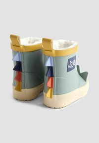 Zelené gumové dažďové čižmy s mäkkým bielym podšívkou, žltým lemovaním a viacfarebnými trojuholníkovými akcentmi na zadnej strane. Logo značky na boku.