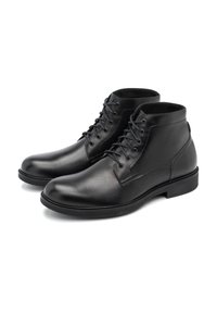 Botas de tobillo de cuero negro con un acabado liso, puntera redondeada, diseño de cordones y un tacón bajo apilado. Interior forrado para mayor comodidad.