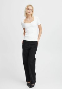 White ribbed short-sleeve top with a square neckline, paired with high-waisted black wide-leg pants and pointed black flats.