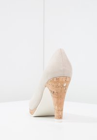 Beige suede high heel shoe with a cork-textured conical heel, featuring a pointed toe and smooth white sole.