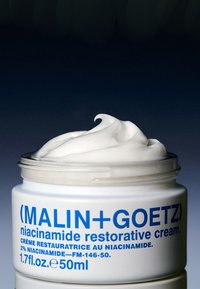 Weißer Behälter mit klarem Deckel, der eine dicke, cremige, weiße Feuchtigkeitscreme enthält. Blaue Schrift weist auf Marke und Produktdetails hin. Größe 50 ml.