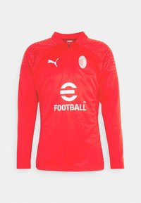 Czerwony sweter piłkarski wykonany z teksturowanej tkaniny, z długimi rękawami, zamkiem błyskawicznym do jednej czwartej oraz białymi elementami logo, w tym słowem "FOOTBALL".
