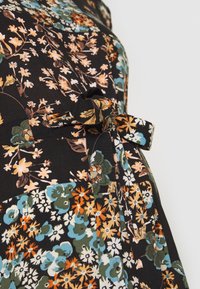 Black fabric dress featuring a floral pattern in orange, blue, and green, with a tied detail at the waist and a soft, textured finish.