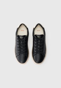 Μαύρα δερμάτινα αθλητικά παπούτσια με κορδόνια στο ίδιο χρώμα, μπεζ λεπτομέρειες στη φτέρνα και λογότυπο στη γλώσσα του παπουτσιού. Λείο υλικό και στρογγυλεμένη μύτη.