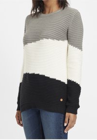 Šedý, bílý a černě pruhovaný pletený svetr s vroubkovanou strukturou a kulatým výstřihem; obsahuje malé kruhové logo na lemu.