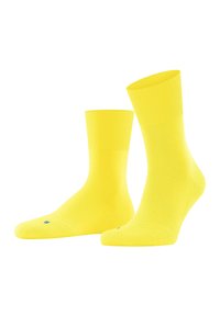 Gelbe Baumwollsocken mit geripptem Bund und verstärktem Zehenbereich. Sie haben eine glatte Textur und ein kleines blaues Logo auf den Zehen.